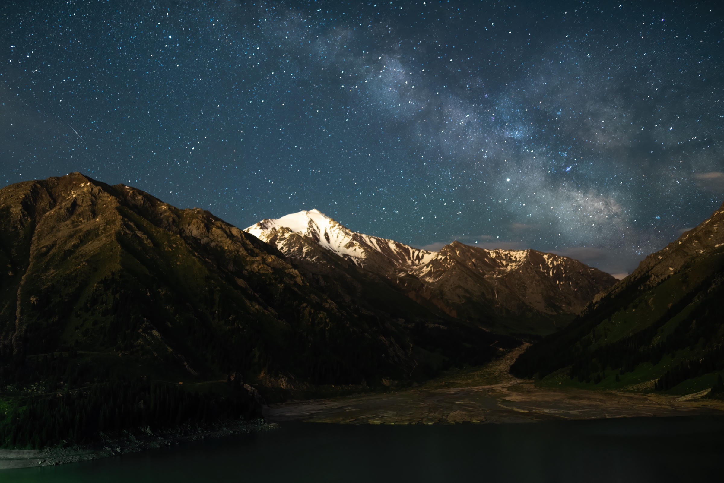 The Milky Way over the snow-capped peak above Big Almaty Lake at night