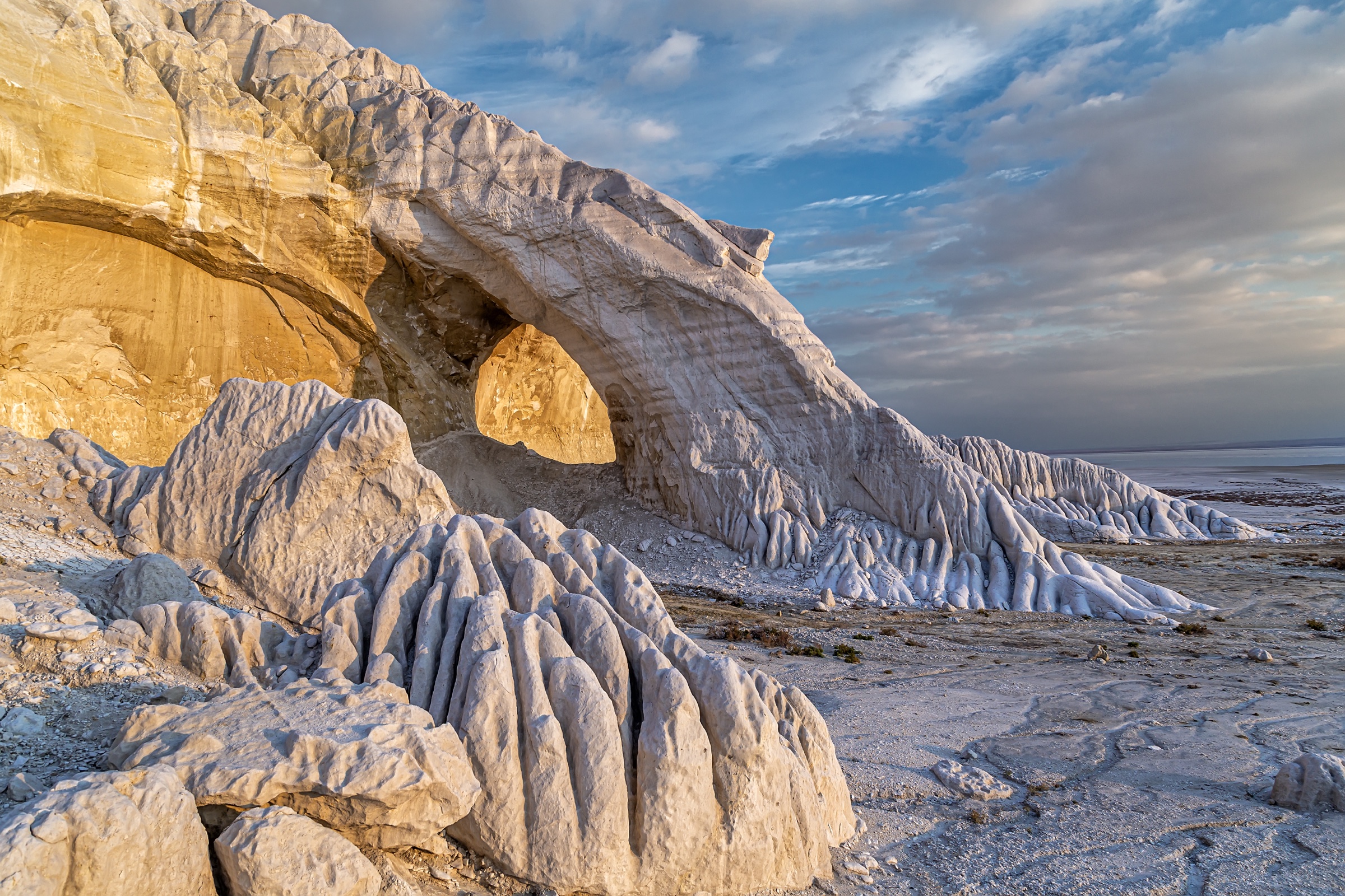 White chalk arch of Tuzbair glowing gold above the salt flat